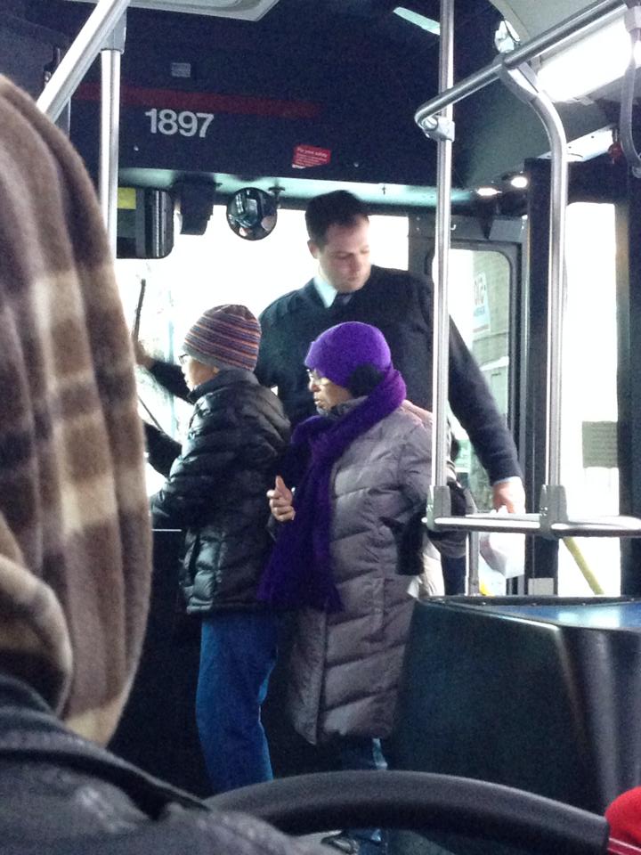 A bus driver getting off the bus to help the elderly over the snow
